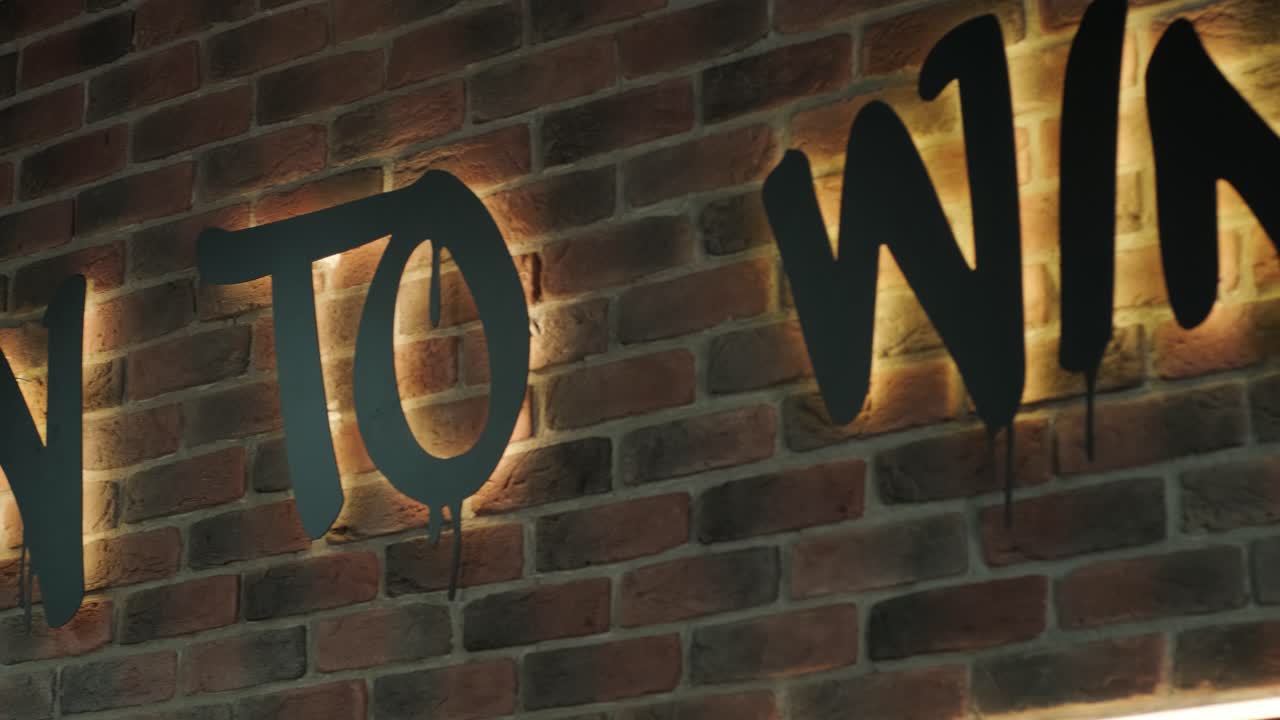 letrero iluminado "nacido para ganar" en la pared de ladrillo