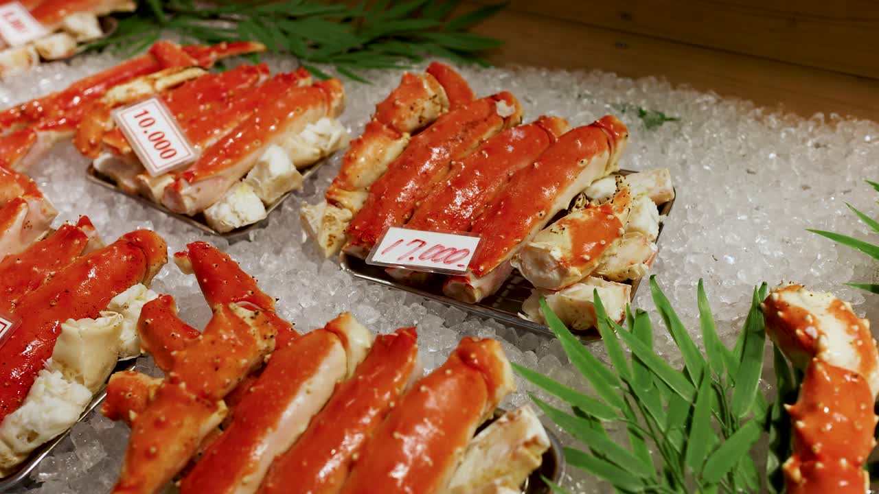 Close-up shot of red king crab legs displayed on crushed ice with bamboo leaves