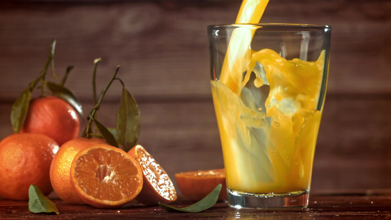 Fresh Tangerine Juice Pouring into a Glass in Slow Motion