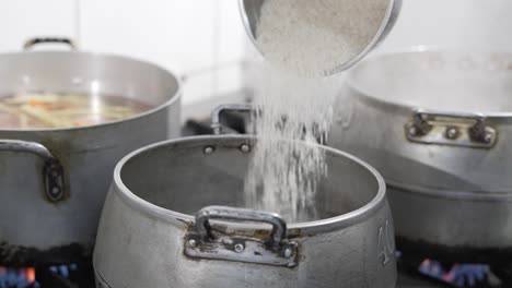 rice pouring into a boiling pot in a bustling kitchen