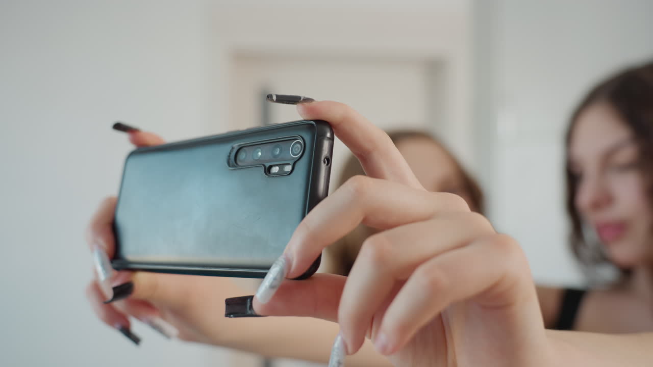 Horizontal Shot By Creators, Steady Hands Capturing Video With Visible Camera Lenses, Artists Filming Social Media Video Using Phone In Relaxed Studio Environment While Holding Horizontally