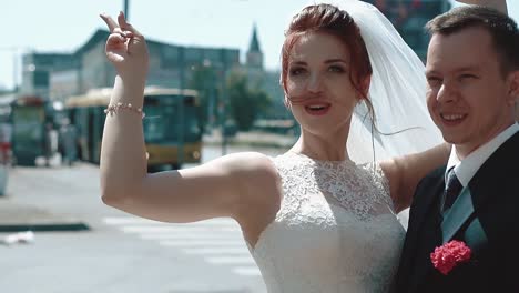newlyweds stand in the city the bride rejoices raises her hand up then hugs the groom close up