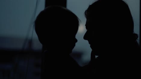 Young-mother-plays-with-her-baby-on-the-window-background