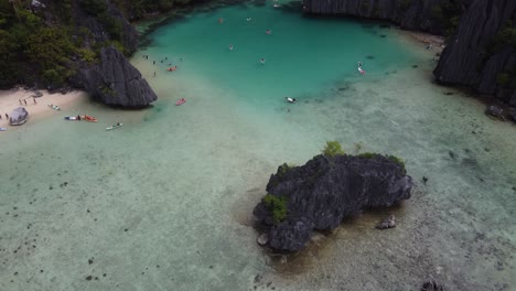 Aerial-tilt-up-view-of-Cadlao-Lagoon-also-called-Ubugon-Cove-on-Cadlao-island,-jagged-limestone-karsts,-part-of-island-hopping-Tour-D-in-El-Nido-Palawan