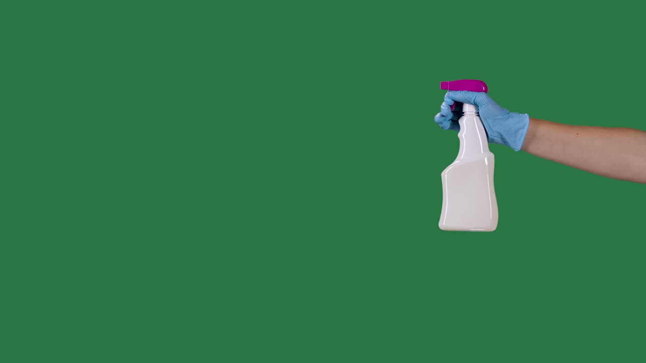 Man in protective gloves sprays a cleaning hygienic spray for disinfection and prevention of COVID 19. Green screen, chroma key. Slow motion. Close up