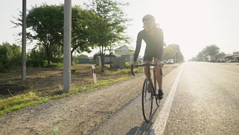 a male professional cyclist rides bicycle along the countryside road