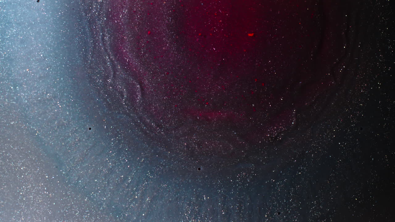 Swirling ink blending with metallic blue and red hues, capturing mesmerizing macro details