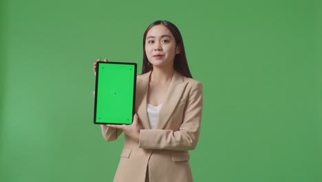 an asian business woman showing tablet green screen on green screen background in the studio