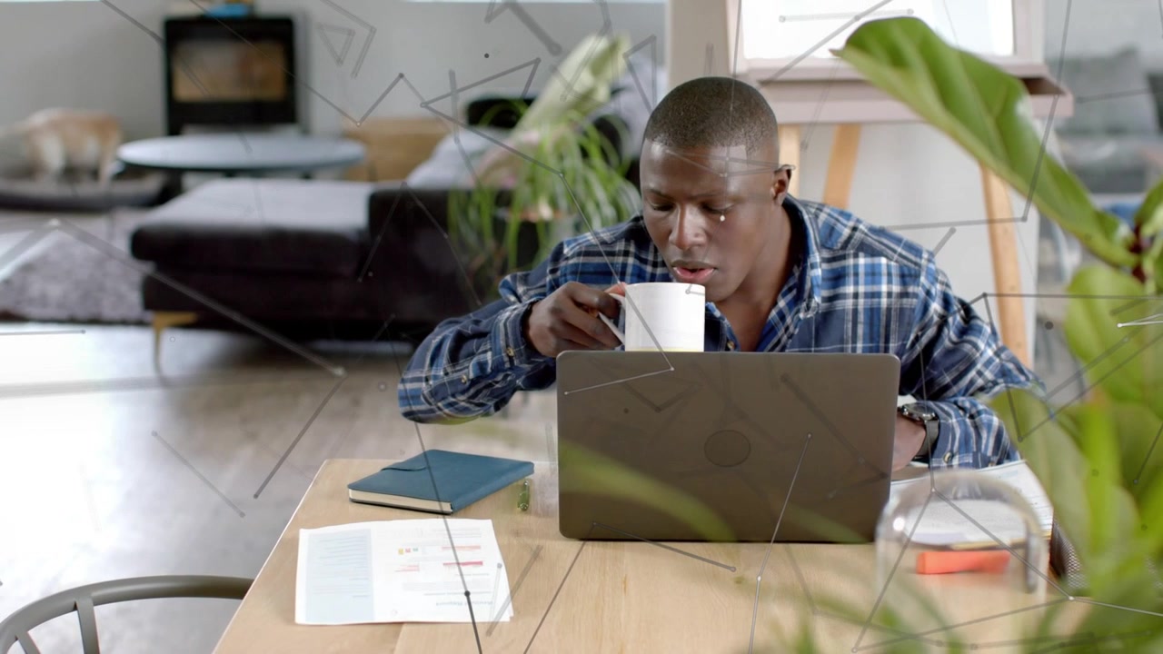 Man glancing at notes, reaching for mug, sipping while working in tech overlay lines tracking focus