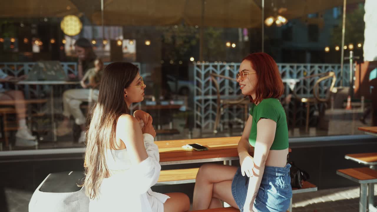 dos amigas hablando al aire libre en un café