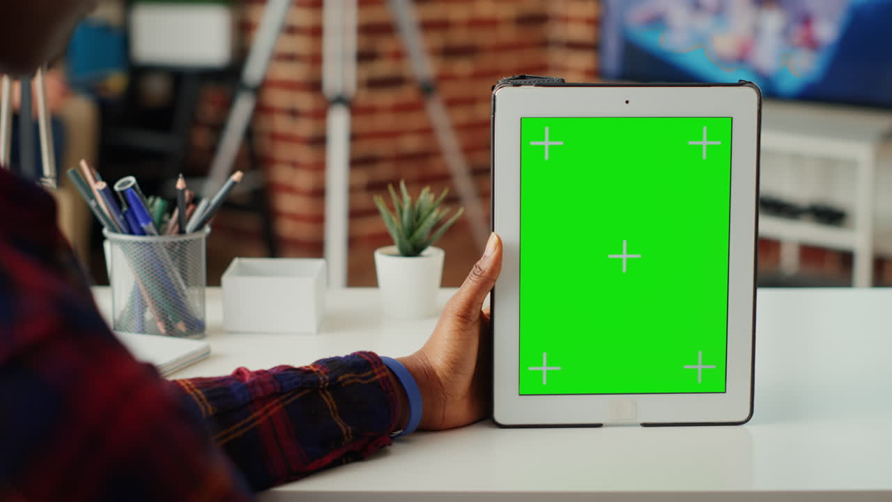 Office worker vertically holding digital device with greenscreen