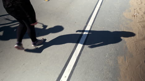 woman taking a stroll on the beach road, with focus on the shadow at santa monica