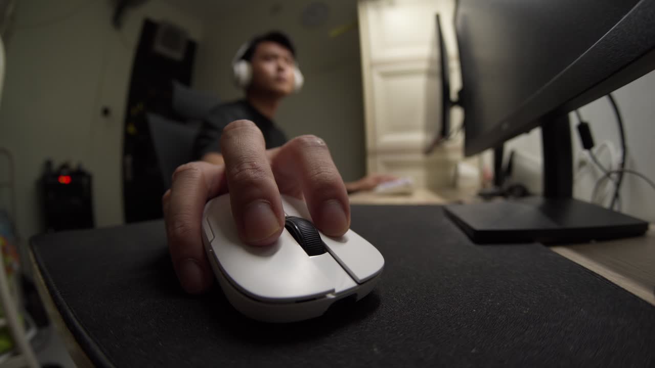 Close-up fisheye view of a moving a white gaming mouse rapidly back and forth in an Indonesian home office. Ideal for gaming, technology, and e-sports content
