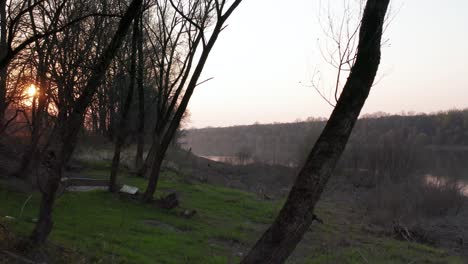 Drone-cinematic-flying-behind-trees-and-capturing-sunset-over-the-river