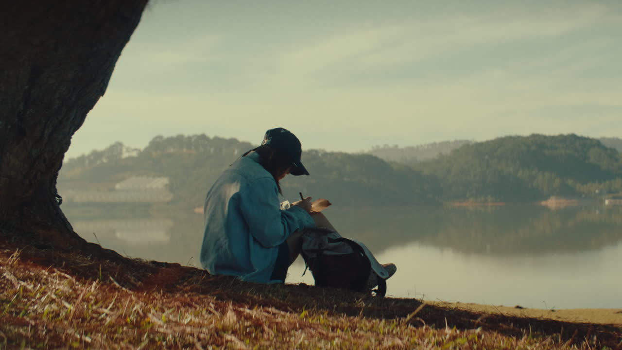 Woman journaling by a lake in nature