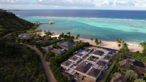 vista aérea de un lujoso resort frente a la playa, una playa tropical y arrecifes de coral en el mar caribe