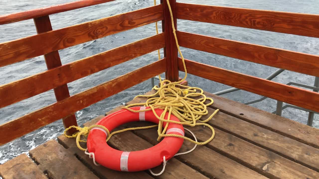 equipo de rescate - boya salvavidas roja con cuerda sobre fondo de agua de mar azul.