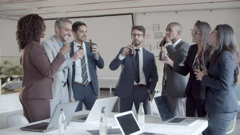 Joyful-office-managers-clinking-beer-bottles