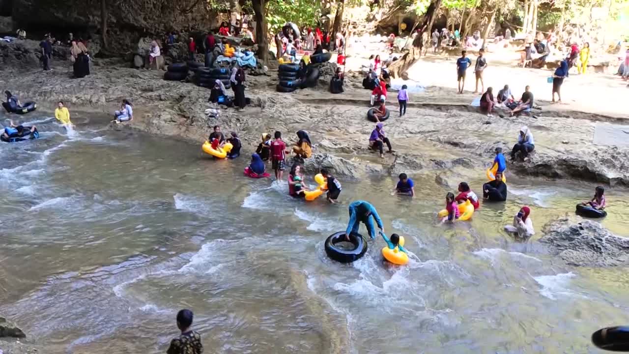 Tourists play water with used tires in front of the Bantimurung waterfall