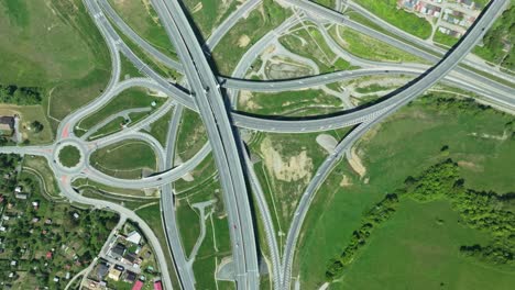 an aerial drone footage captures intricate highway junction with cars navigating complex roundabouts and intersecting roads