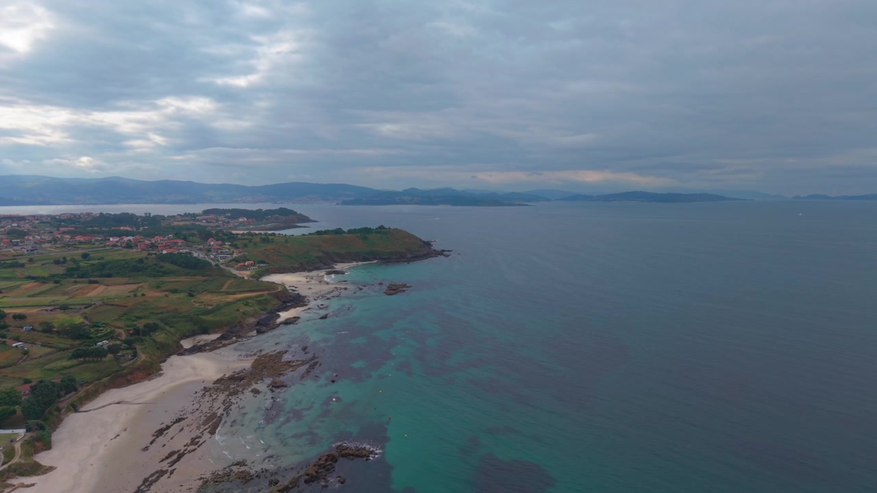 Luftfoto - hvid sandstrand, klipperev, turkise lavvandede områder og grøn forager ved Sanxenxo, Galicien