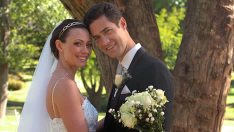 recién casados de pie en el parque