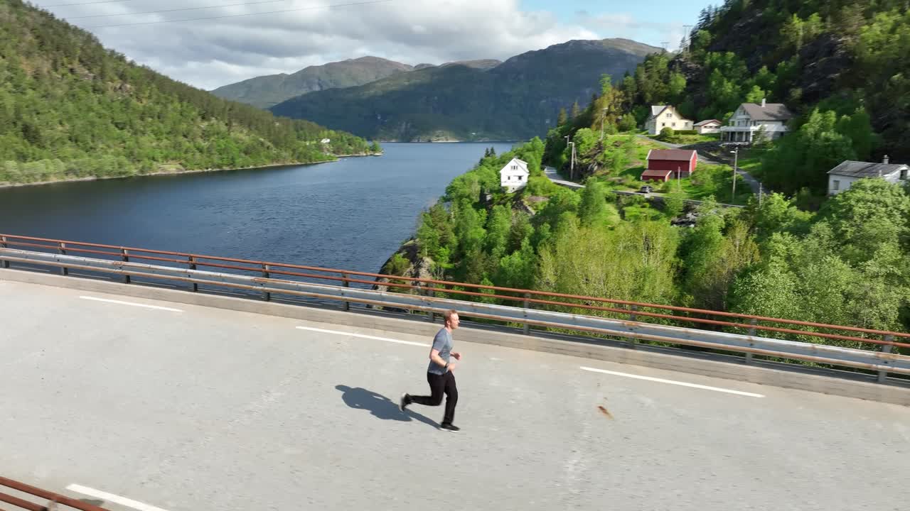 el avión no tripulado vuela alrededor del hombre corriendo en el puente que atraviesa el hermoso fiordo de noruega