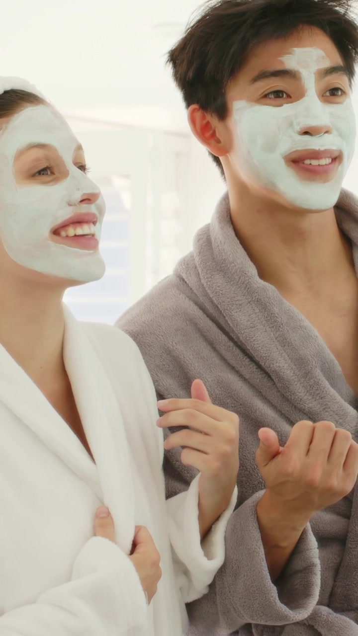 Video vertikal: Pria menunjuk, membuat pasangan tertawa di rumah, mengenakan jubah dan masker selama rutinitas