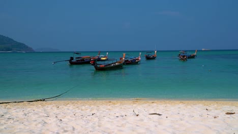 Famous,-traditional-and-iconic-Thai-longtail-boats-on-an-empty-sandy-beach-on-the-remote-island-Koh-Lipe-in-Thailand,-close-to-the-Malaysian-border