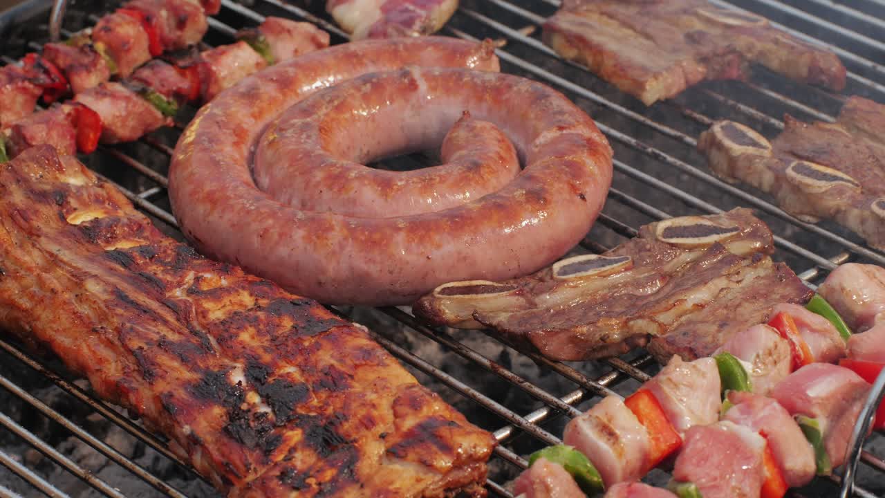 Traditional spanish barbeque, big sausage chorizo botifarra, pork and beef ribs on grill with fire, american style cooking, chef grilling meat fat food, steaks and sausages on bbq. High quality 4k footage