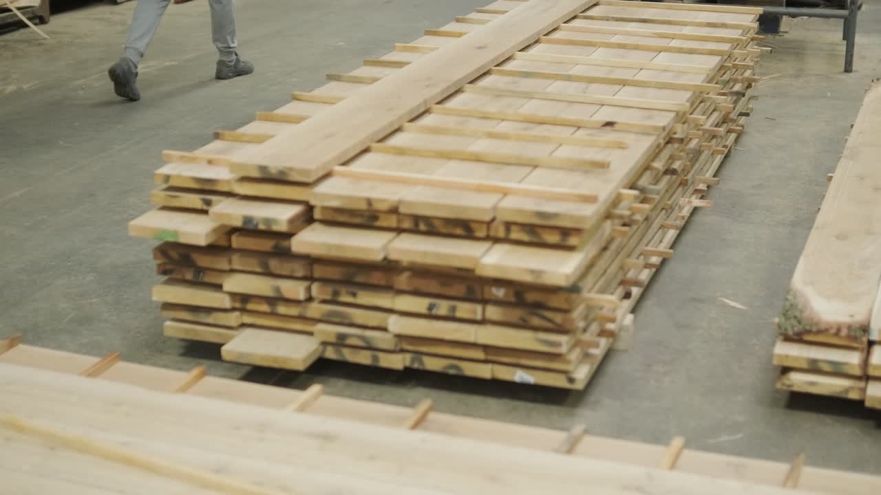 Operaio che impila tavole di legno appena tagliate in una segheria