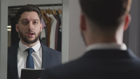 young man in suit at home practising job interview technique reflected in mirror