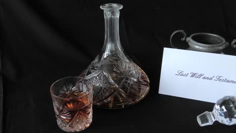 an envelope holding a will is put on a desk beside a glass of whisky and whisky decanter