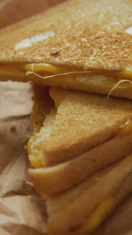video de primer plano de sándwiches de queso tostado en papel marrón sobre un fondo gris
