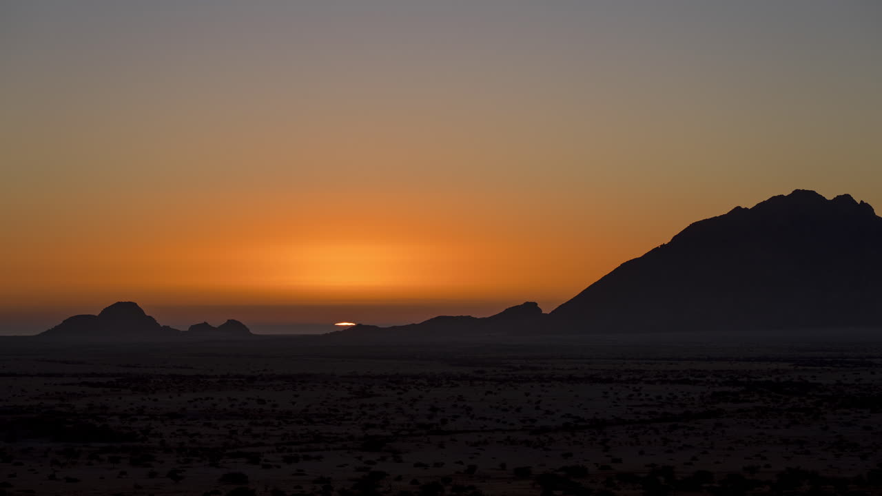 hermosa puesta de sol de verano con cielo de colores cálidos detrás de la silueta de la montaña de spitzkoppe en namibia