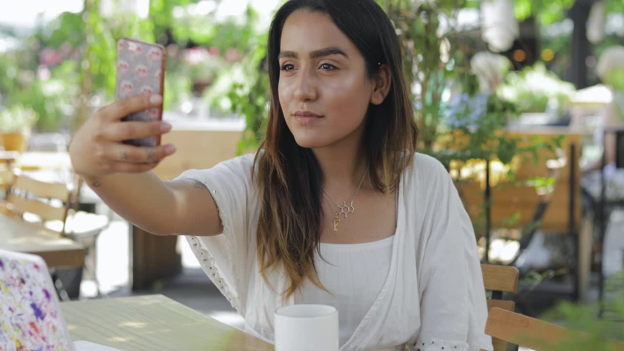 mujer joven en una mesa de restaurante tomando un selfie