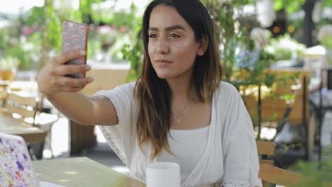 Mujer-Joven-En-Una-Mesa-De-Restaurante-Tomando-Una-Selfie