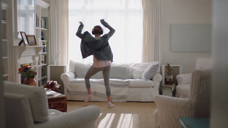 happy young woman dancing at home having fun listening to music wearing headphones enjoying weekend celebration with funky dance moves