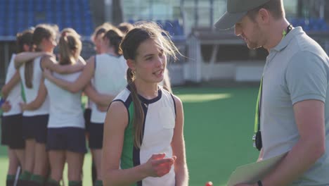 hockey coach talking with female player on the field