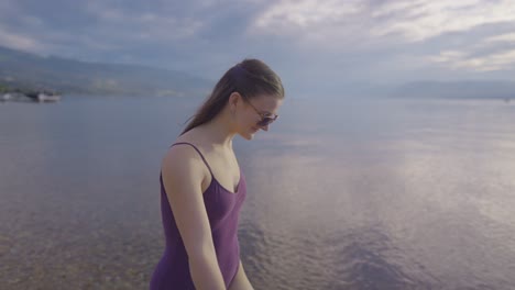 Side-close-view-of-smiling-young-girl-playing-by-mountain-lake