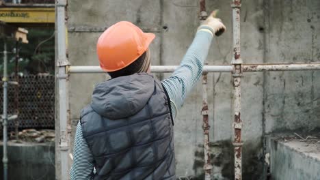 trabajador de la construcción inspeccionando el andamio en una pared de hormigón.