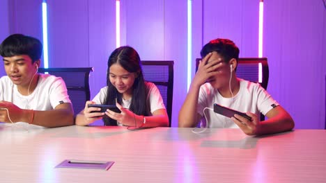 team of asian esport gamers playing in competitive video games on a cyber games tournament by mobile phone