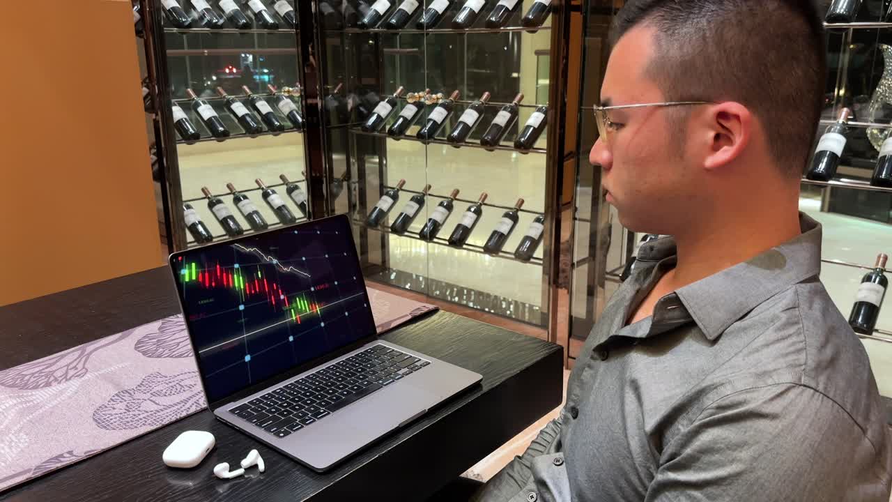 Asian Millennial Man Watching Bear Market Candlesticks Fall on Laptop inside Luxurious Home