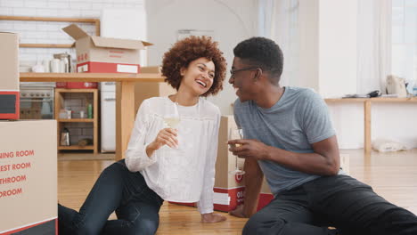 Portrait-Of-Couple-Celebrating-Moving-Into-New-Home-With-Glass-Of-Wine