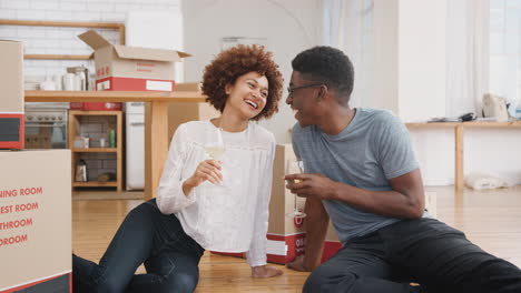 portrait of couple celebrating moving into new home with glass of wine