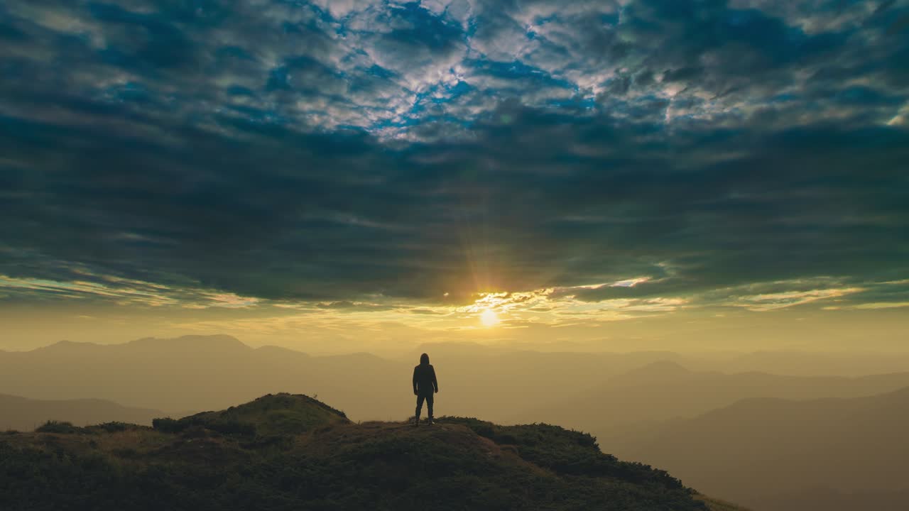 el hombre de pie en una montaña contra un sol brillante. lapso de tiempo