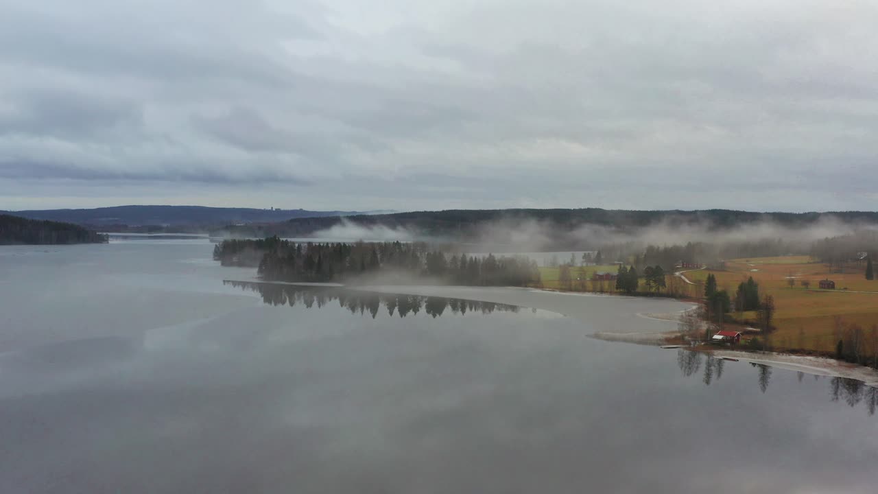 Flying through the fog above a partially frozen lake at the start of the winter
