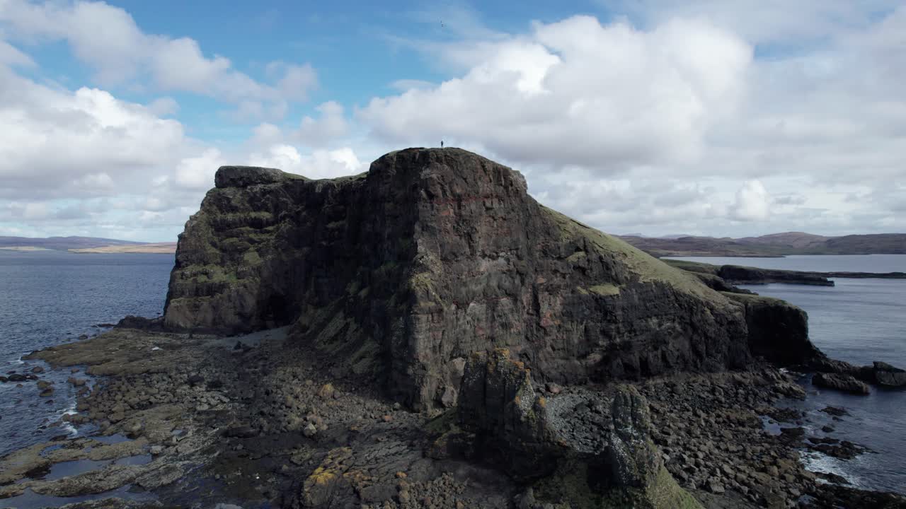 Ampia ripresa panoramica con drone di una persona in piedi sull'isola di Oronsay in una giornata di sole in Scozia.