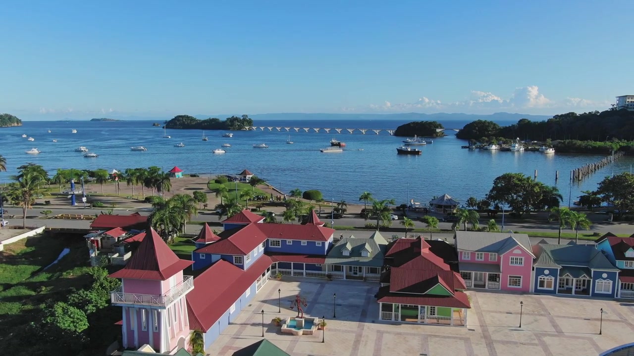 Flygfoto som visar färgglada kolonialhus i Santa Barbara Samaná med båtar i bakgrunden under en solig dag.