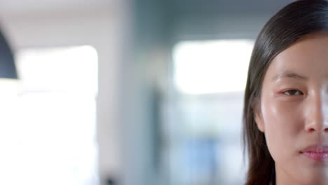 Half-portrait-of-happy-asian-businesswoman-at-office,-smiling-in-slow-motion,-copy-space